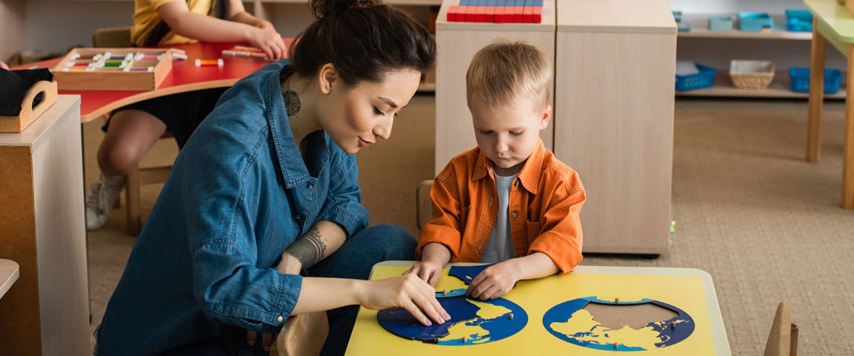 young teacher helping boy combining earth map puzzle, banner