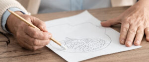 panoramic shot of retired woman holding paper with drawing of brain on table