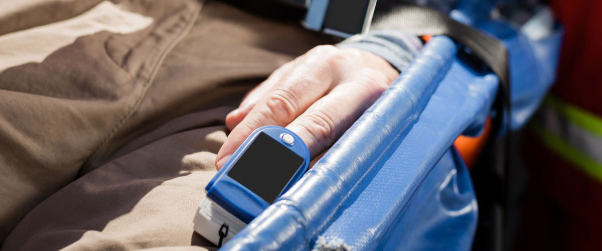 senior man with heart rate monitor lying on stretcher