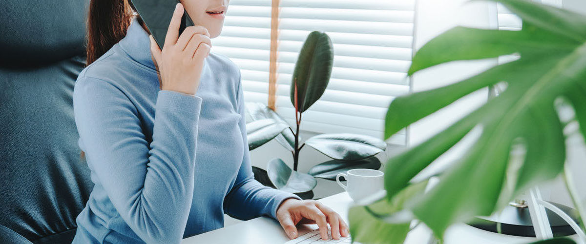 Asian woman working from home using computer and drinking coffee