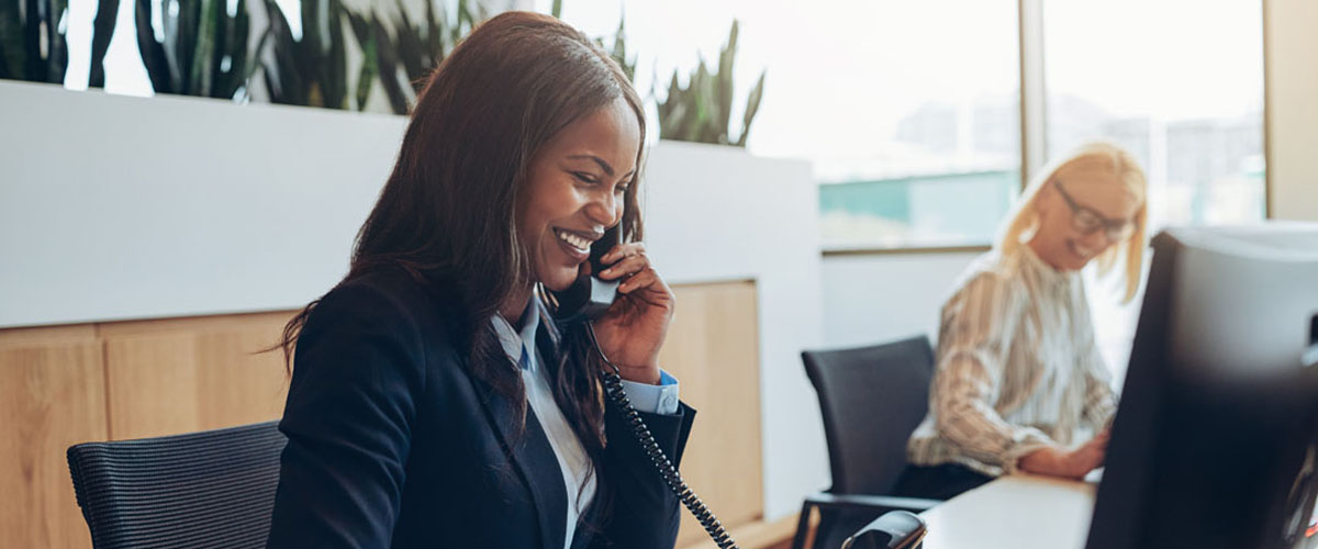 Laughing African American businesswoman talking to clients on a telephone